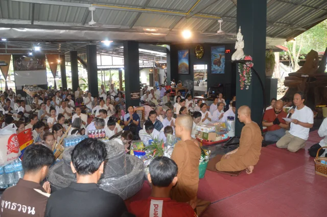 ພຣະສົງນັ່ງຮັບເຄື່ອງຖວາຍ ຂະນະຜູ້ນຳບຸນອ່ານຊື່ເຈົ້າພາບສະຫຼາກ.