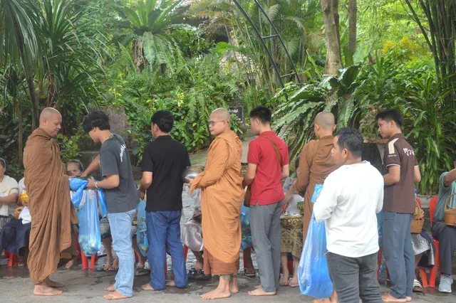 ພຣະສົງແຕ່ລະອົງຍ່າງຮັບເຄື່ອງຖວາຍຕາມແຖວຍາດໂຍມ.