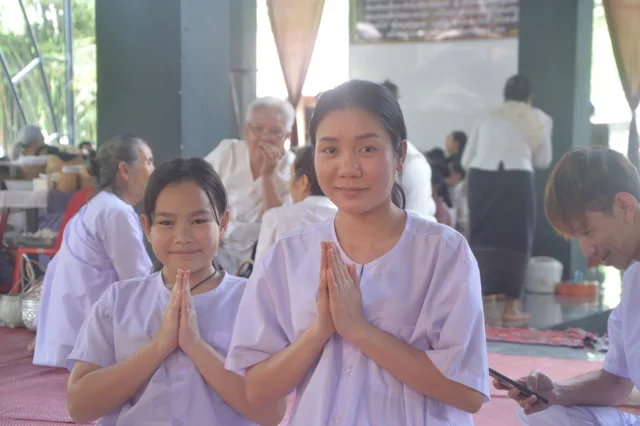 ເດັກນ້ອຍ ແລະ ຍາດໂຍມນຸ່ງຂາວພະນົມມືດ້ວຍຄວາມສັດທາ.
