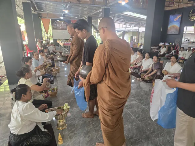 ພຣະສົງຮັບບິນທະບາດຈາກຍາດໂຍມພາຍໃນສາລາ.